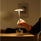 Hand touching cordless LED table lamp base with warm glowing round top shade