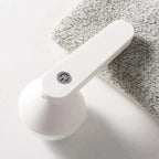 Rechargeable fabric shaver, white handheld lint remover on grey knitted cloth