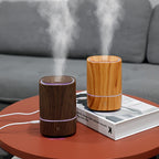 Woodgrain aromatherapy diffuser producing cool mist vapor, orange and dark finishes