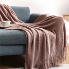 Mauve pink knit throw blanket with fringe tassels, draped over a couch arm