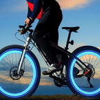 A person riding a black mountain bike outdoors at sunset, with the bicycle's wheels illuminated by bright blue LED light rings against a blue sky.