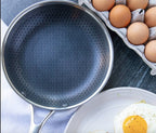 Non-stick skillet interior with dark honeycomb pattern, eggs visible beside pan