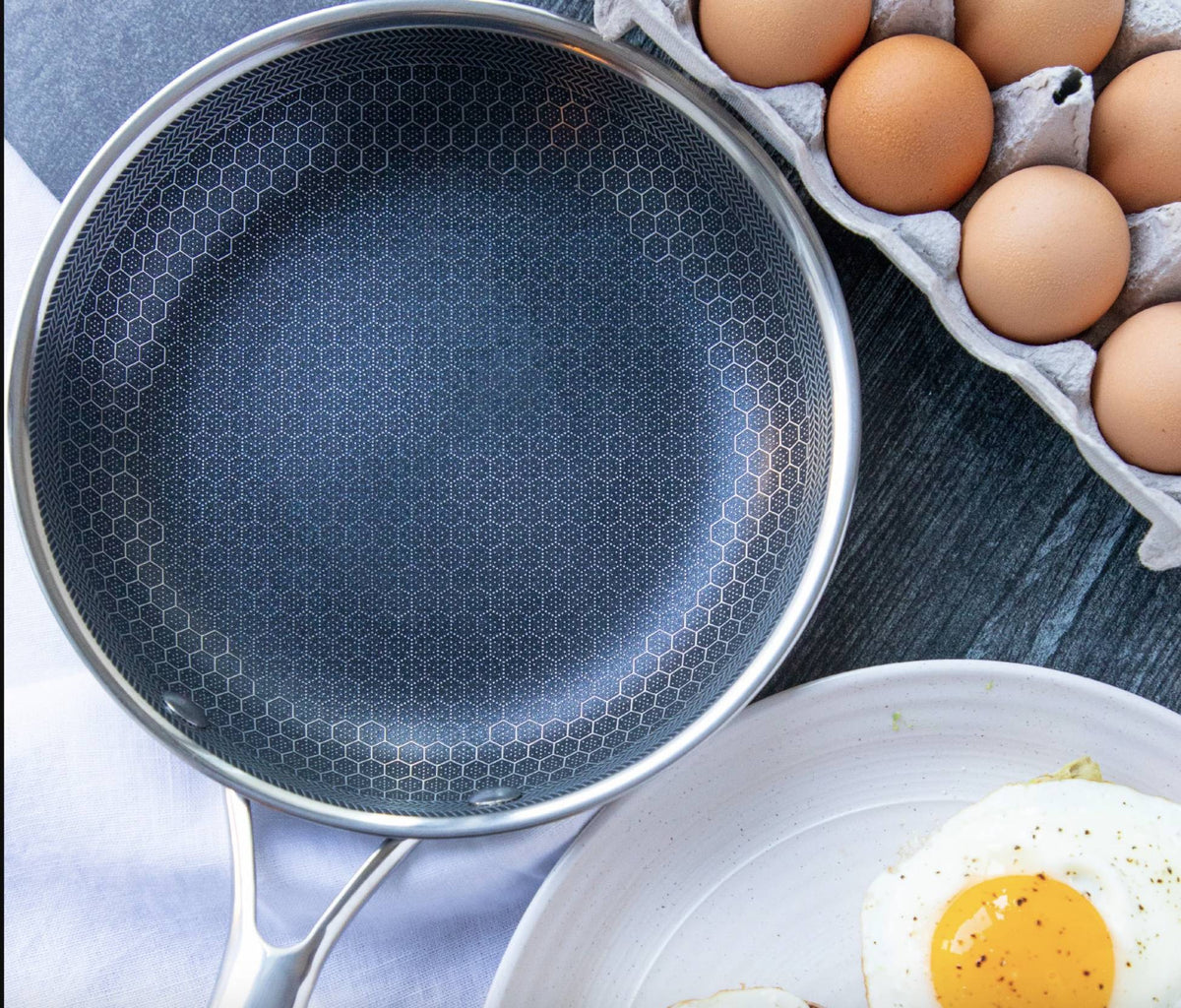 Non-stick skillet interior with dark honeycomb pattern, eggs visible beside pan