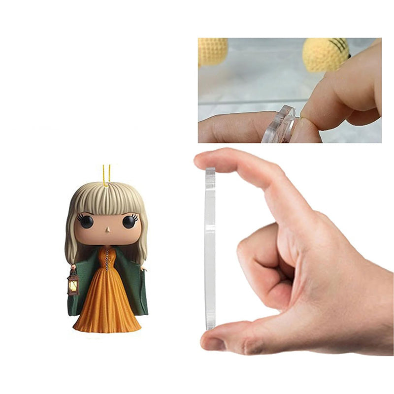 Pop star 2D charm figure with hanging string, shown being assembled by hand
