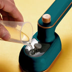 Green mini steam iron dispensing steam from water tank opening