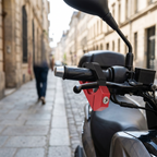 Scooter handlebar steering lock with black clamp and red locking body on scooter handlebar